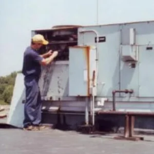 A man in yellow hat and blue shirt working on an air conditioner.