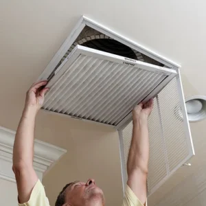 A man is holding an air filter up to the ceiling.